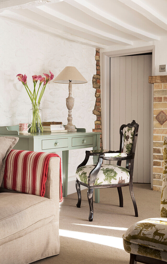 Upholstered armchair at painted desk with calla lilies and exposed brickwork in London home,  England,  UK