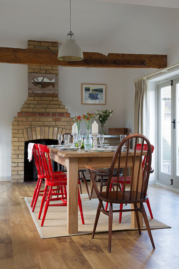 Hölzerner Esstisch mit bemalten Stühlen und freiliegender Backsteinschornstein in einem Londoner Haus, England, UK