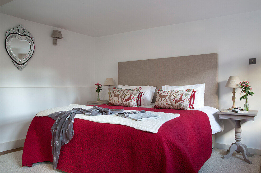 Morgenmantel und Zeitschrift auf Doppelbett mit rotem Bezug in Londoner Wohnung, England, UK