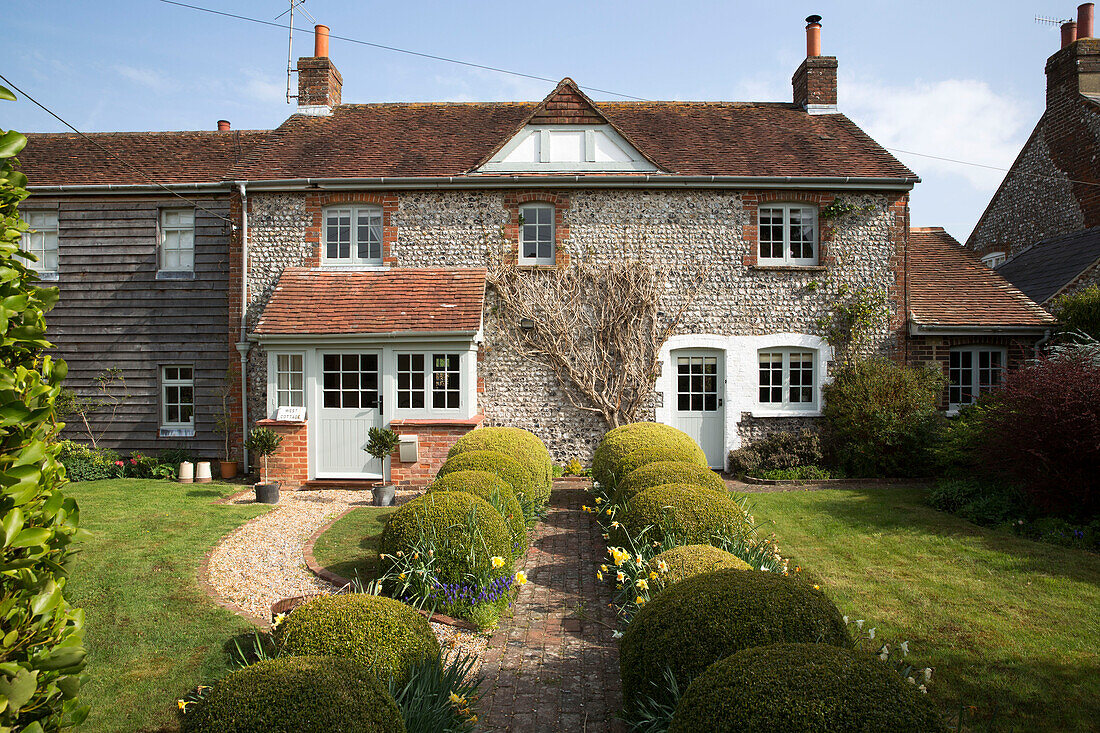 Ziegelpfad mit Formschnitthecke vor einem freistehenden Haus in East Dean, West Sussex, Vereinigtes Königreich