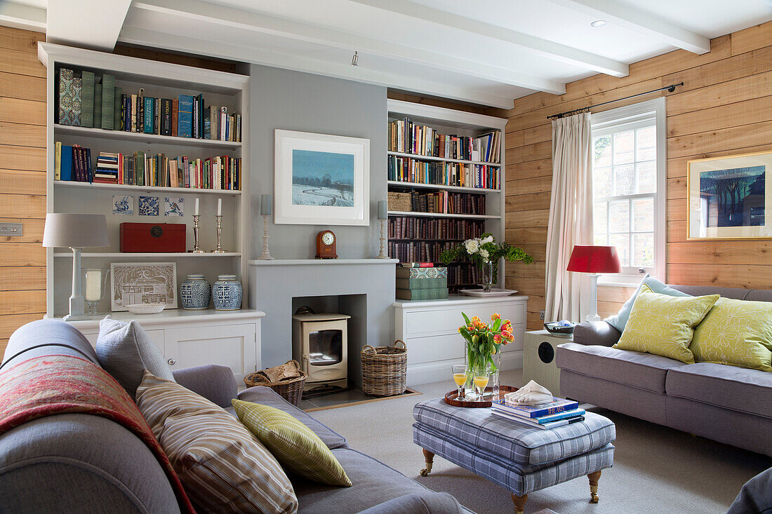 Hellgraue Sofas in einem holzgetäfelten Wohnzimmer in einem Haus in Surrey, England, UK