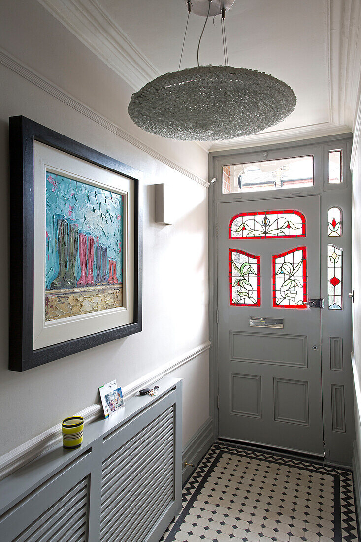 Kunstwerk über der Heizkörperabdeckung im gefliesten Eingangsflur eines modernen Londoner Hauses, England, UK