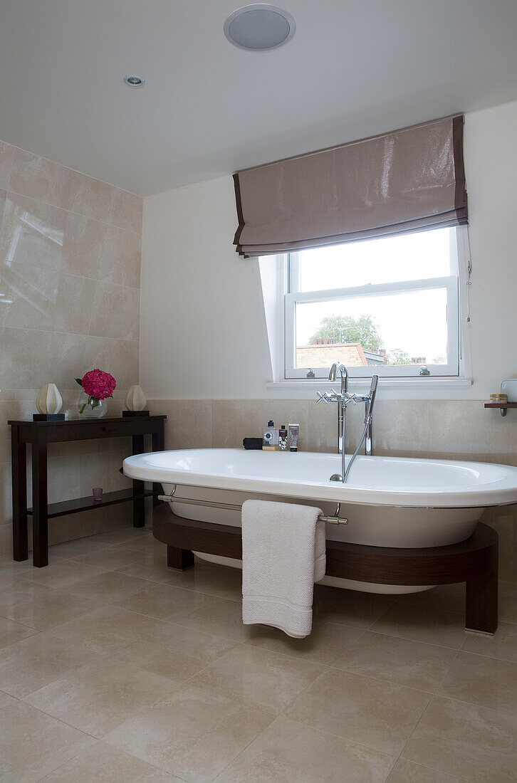 Freestanding bath with towel rack at window of contemporary London home, England, UK