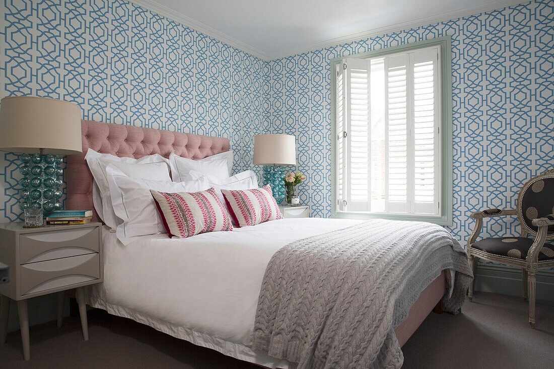 Rosa Kopfteil und Wolldecke auf Doppelbett in blau gemustertem Schlafzimmer in London, England, UK