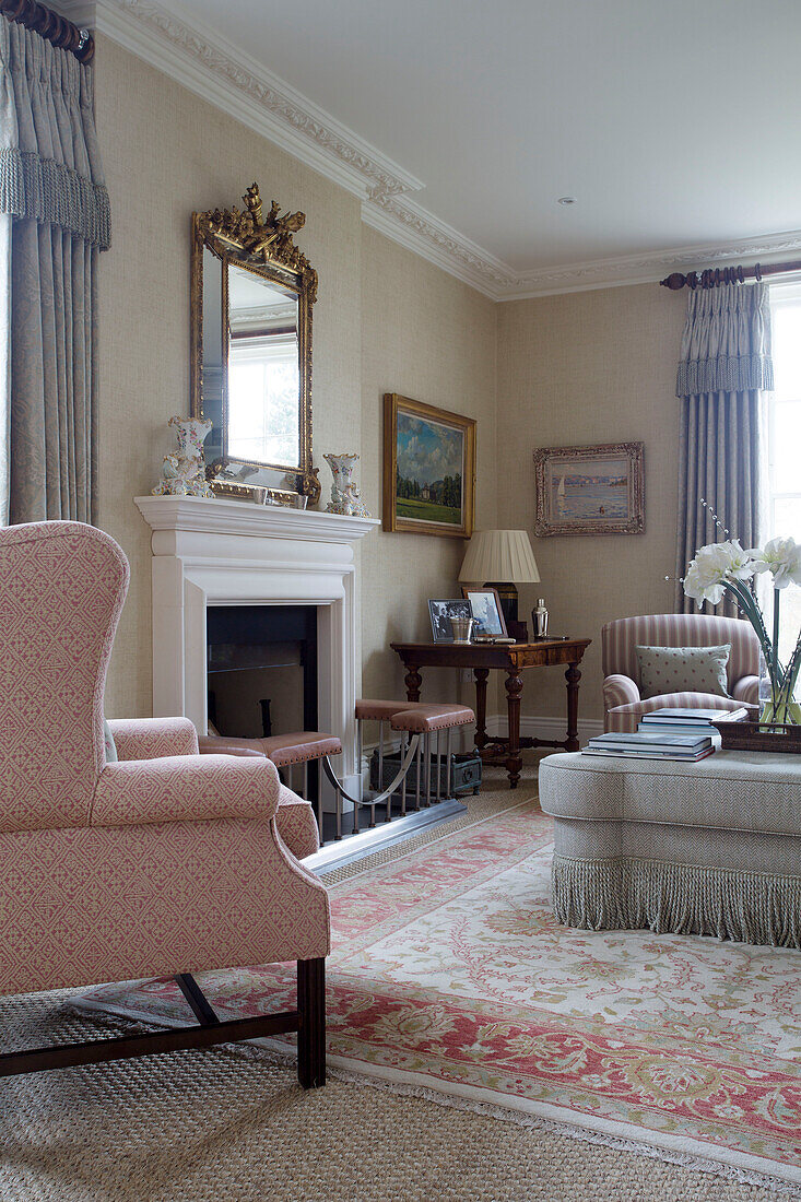Upholstered armchair and ottoman at fireside in Pewsey living room Wiltshire England UK