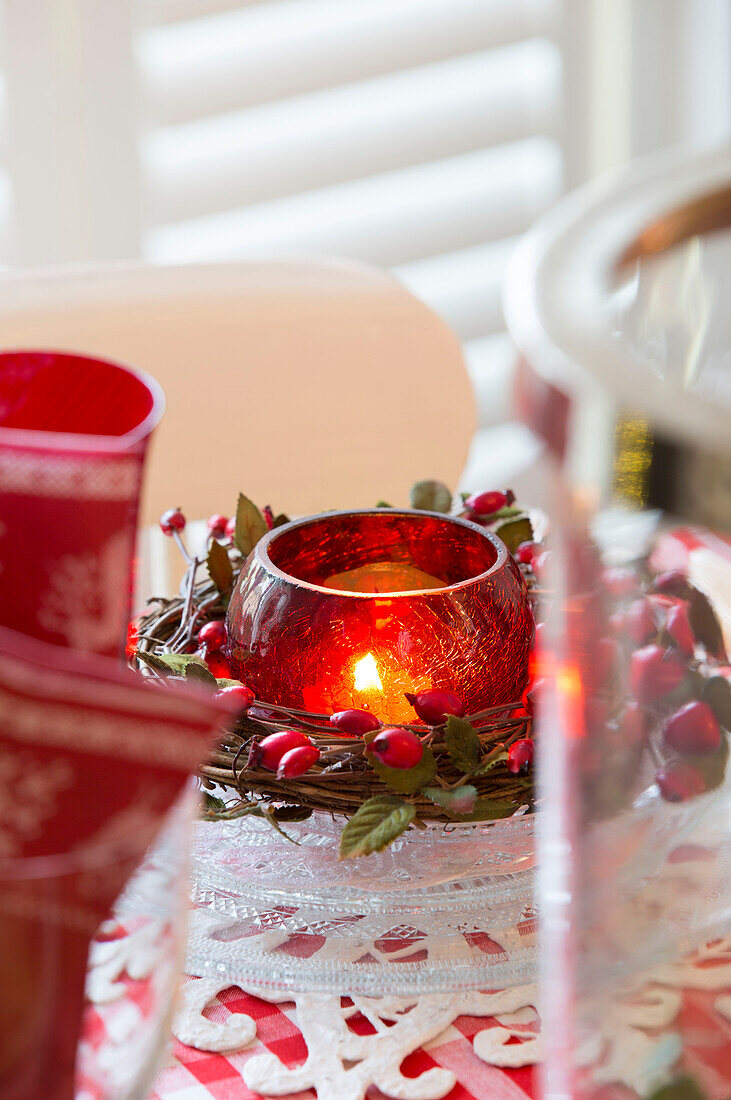 Beleuchtetes Teelicht mit Beeren auf dem Esstisch in einem Haus in Surrey, England UK