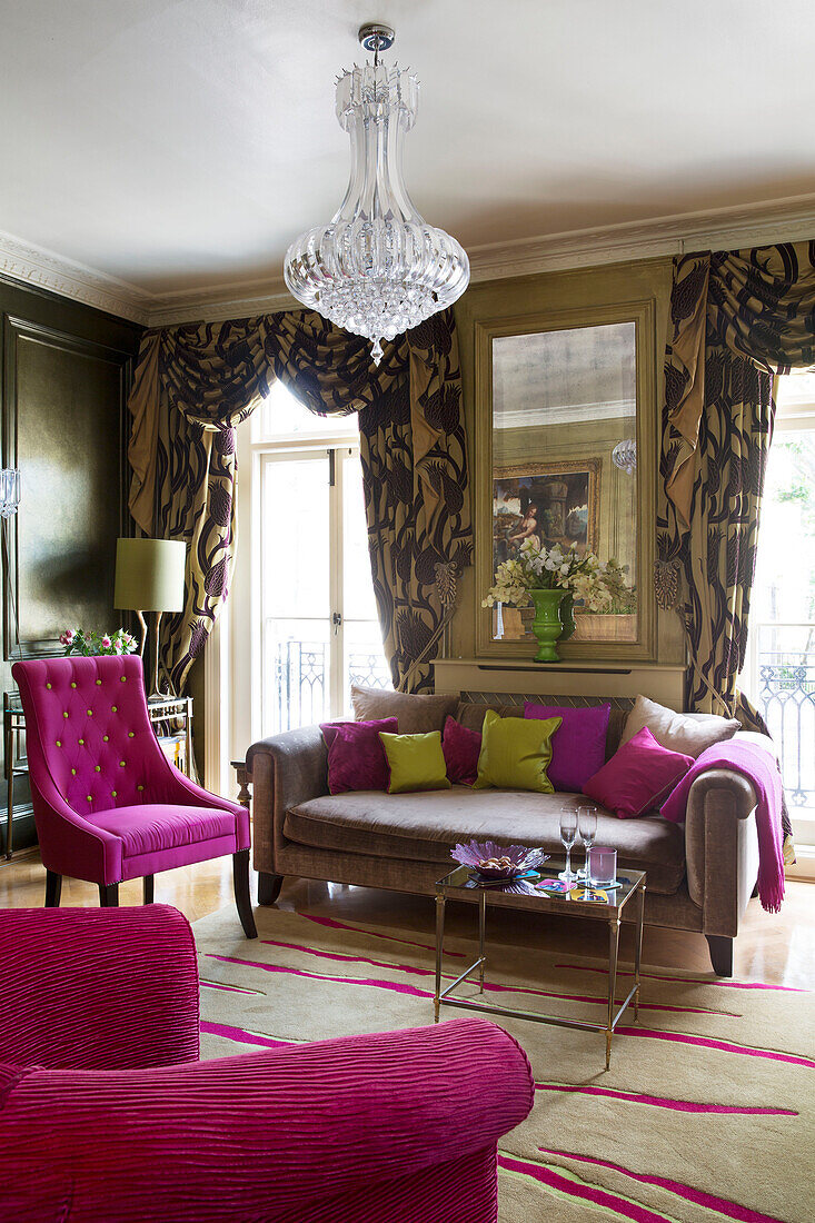 Pink chairs and sofa with patterned curtains in living room of London townhouse   England   UK