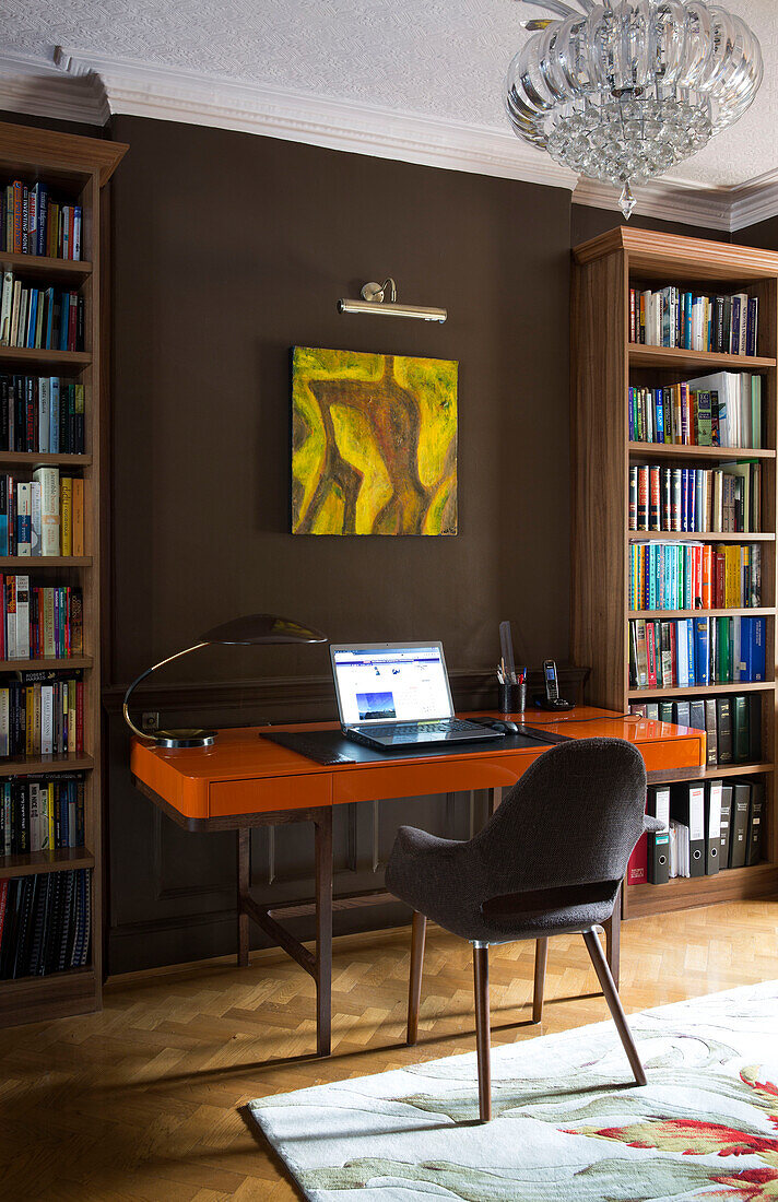 Laptop auf Schreibtisch mit Stuhl und Bücherregalen in Londoner Stadthaus England UK