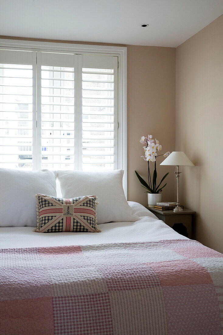 Union Jack Kissen auf rosa Gingham gesteppt Doppelbett an Fensterläden in London Stadthaus England UK