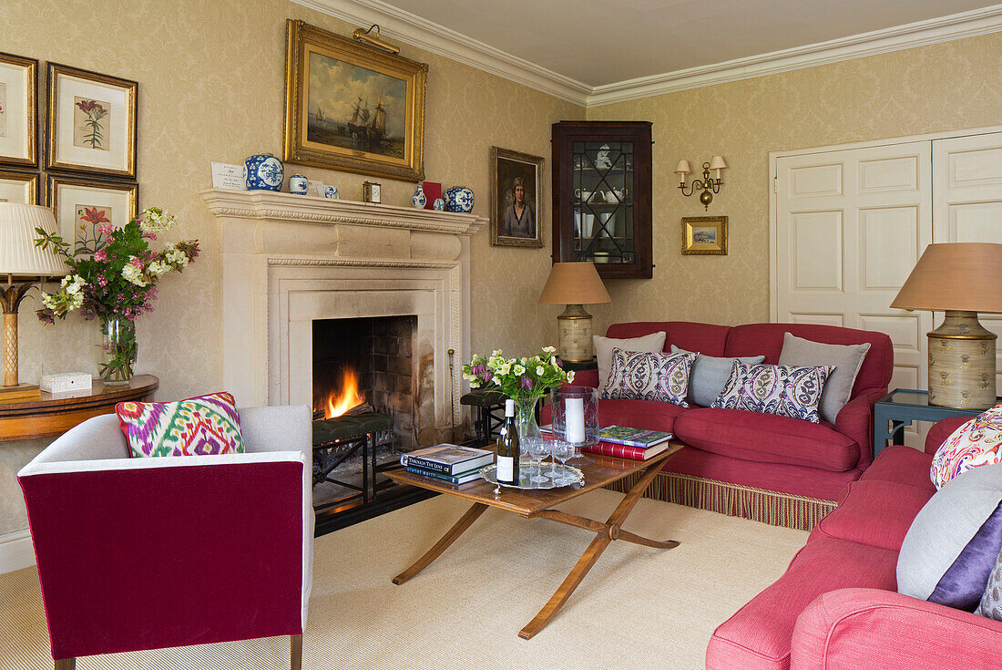 Gilt-framed artwork and lit fore with red furniture in Warminster living room   Wiltshire  England  UK