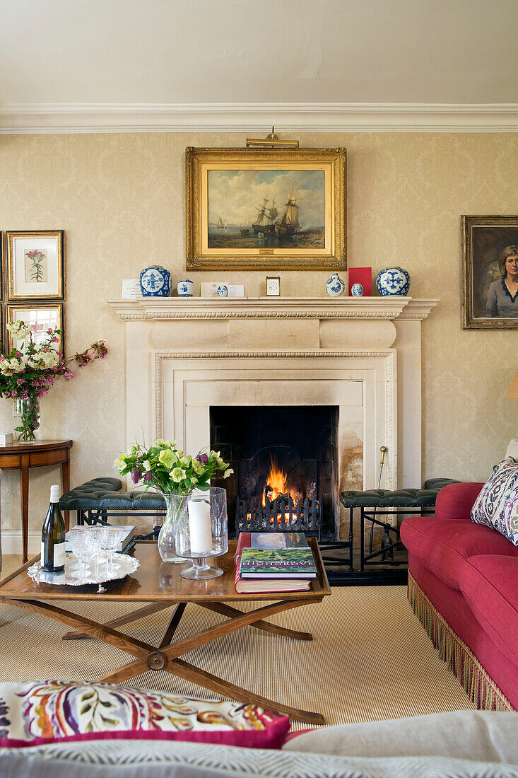 Niedriger hölzerner Couchtisch vor beleuchtetem Feuer im Wohnzimmer von Warminster in Wiltshire, England, Vereinigtes Königreich