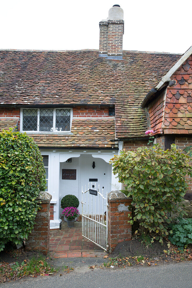 Offenes Tor zur weiß gestrichenen Eingangstür eines gefliesten Landhauses in Surrey, England, UK