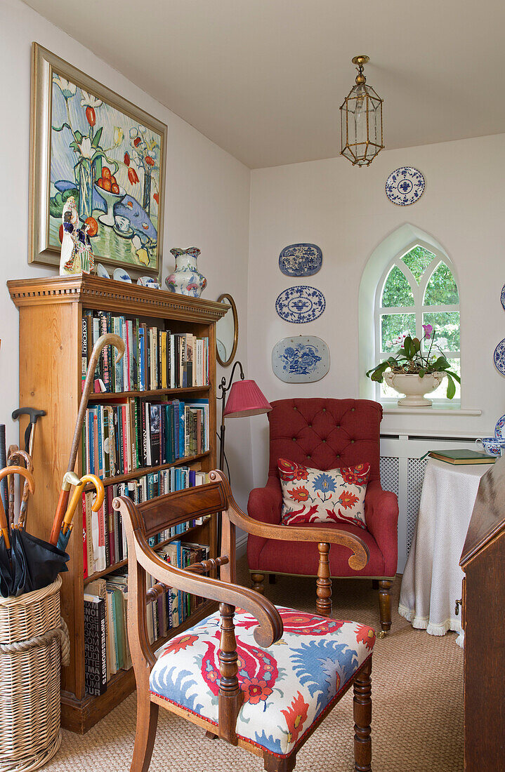Upholstered armchairs and bookcase with walking sticks in Dorset home England UK