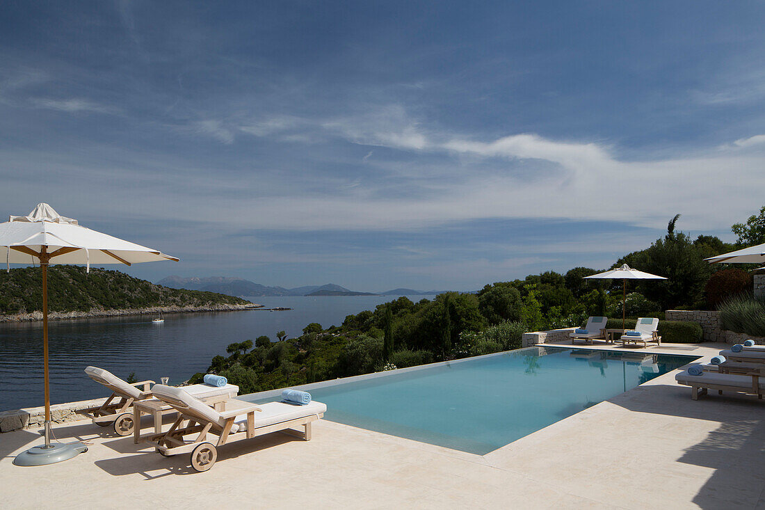 Sunloungers and parasols with seawater pool and view of Aegean sea on Greek island of Ithaca