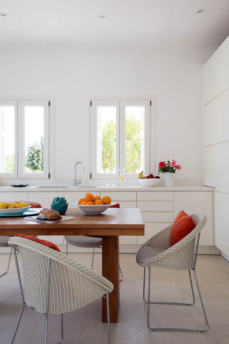 Wicker chairs at wooden table with uncurtained windows in villa on Greek island of Ithaca