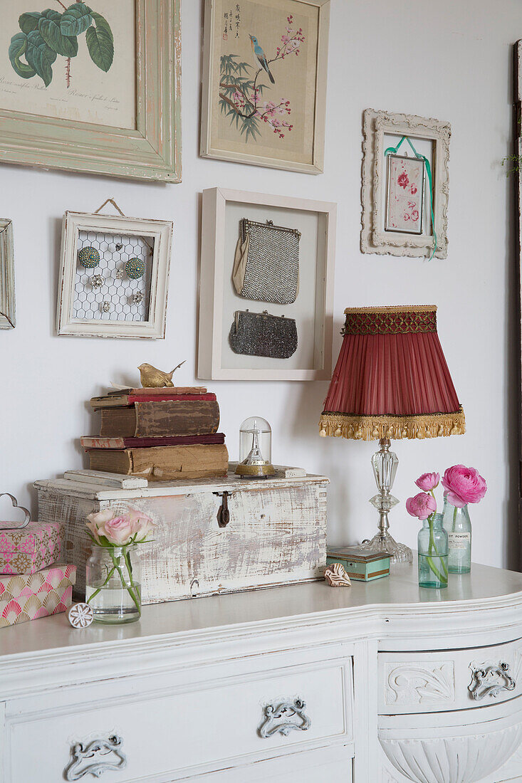 Framed botanical prints above sideboard with red lampshade in Norfolk home England UK