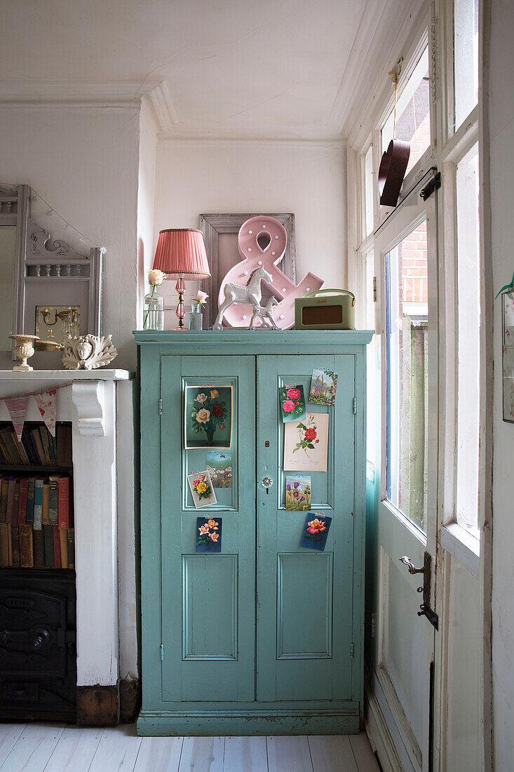 Botanical postcards on blue painted storage cupboard in Norfolk home England UK
