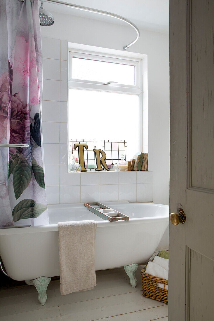 Freistehende Badewanne mit geblümter Duschstange am Fenster in einem Haus in Norfolk England UK