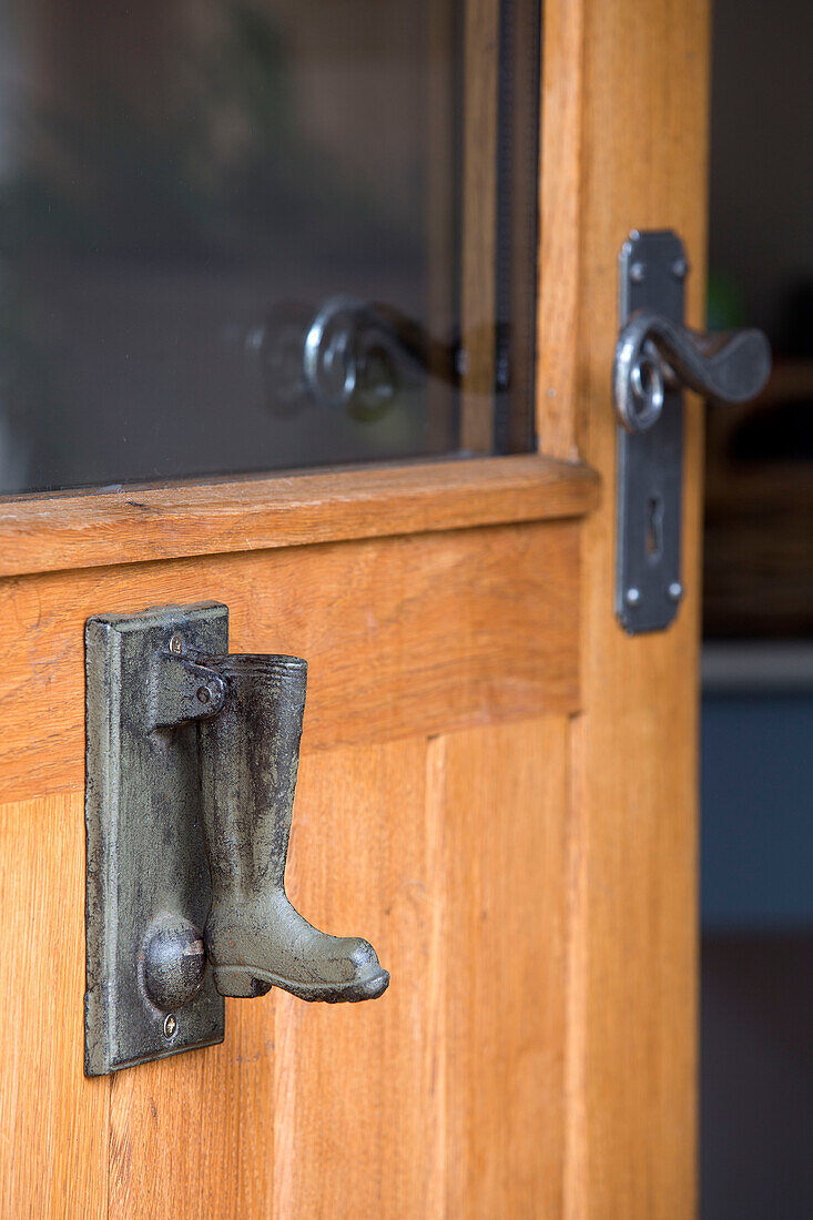 Gummistiefel-Türklopfer an der hölzernen Eingangstür eines Hauses in Surrey, England, UK