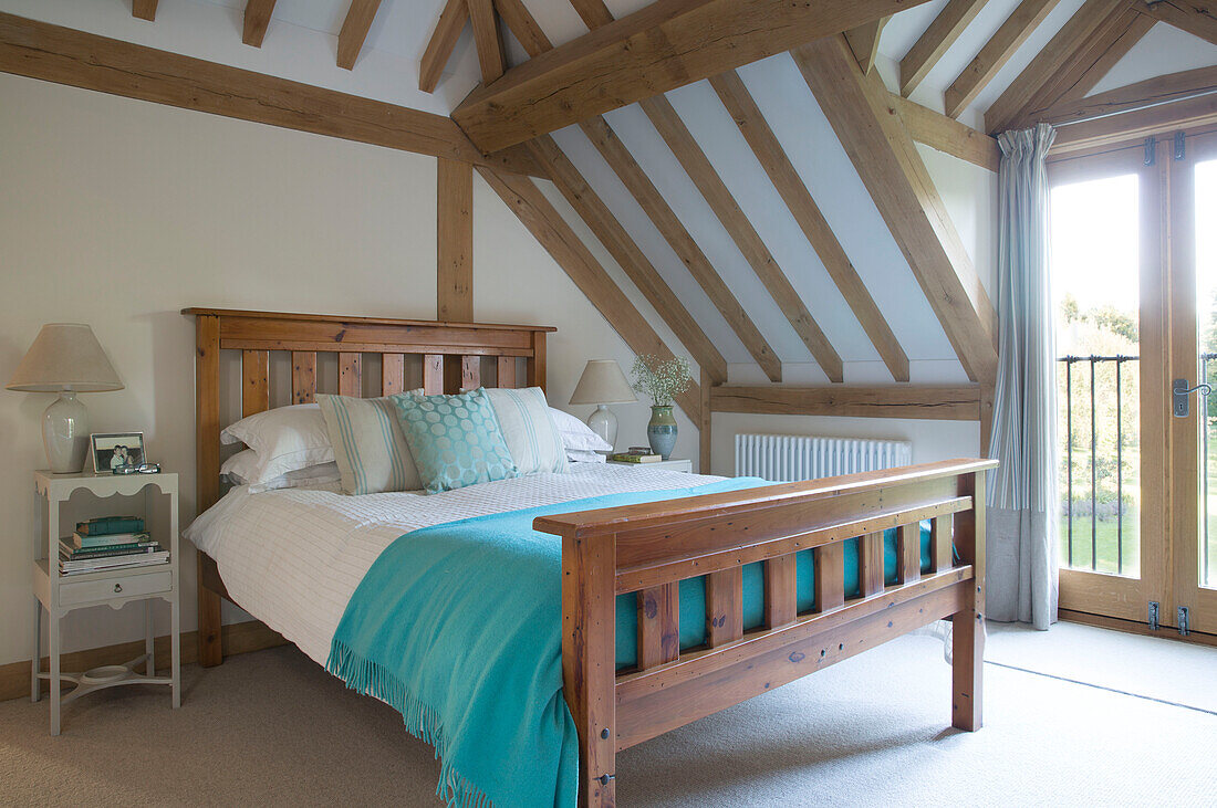 Hellblaue Decke auf einem Doppelbett in einem Haus mit Balken in Surrey, England, UK