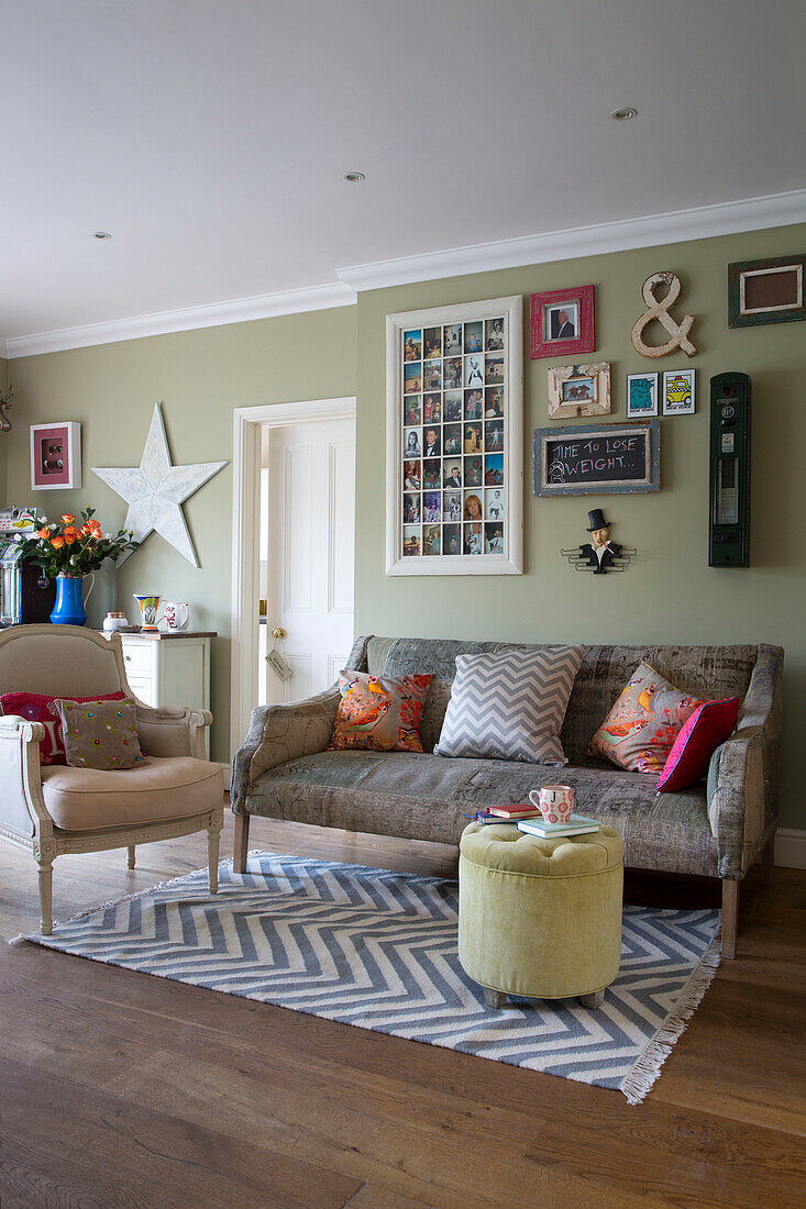 Framed artwork above sofa in wood floored living room with patterned rug in UK home