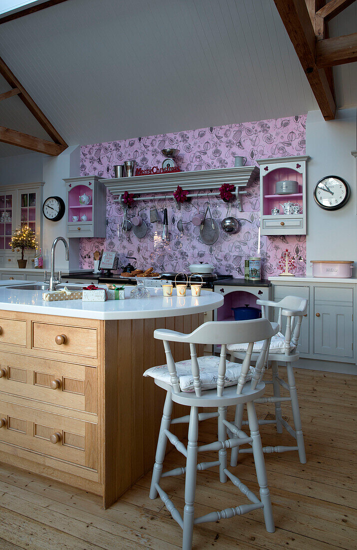 Pink feature wall in open plan kitchen with island unit in Sussex home England UK