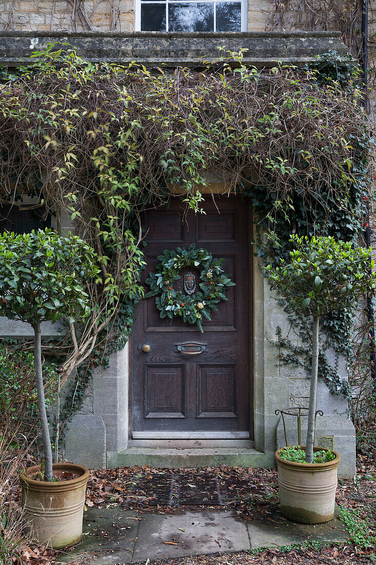 Weihnachtskranz und heruntergefallene Blätter an der Haustür eines Einfamilienhauses in Surrey UK