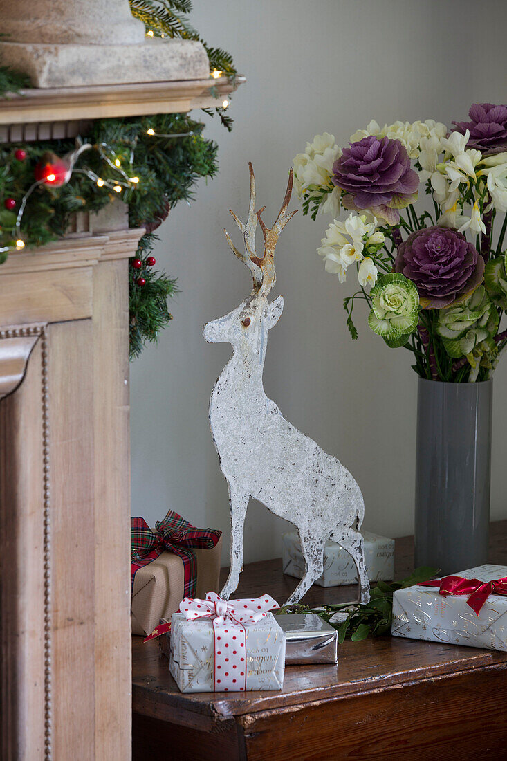 Metallischer Hirsch mit Weihnachtsgeschenken und Schnittblumen in einem Haus in Surrey, England UK