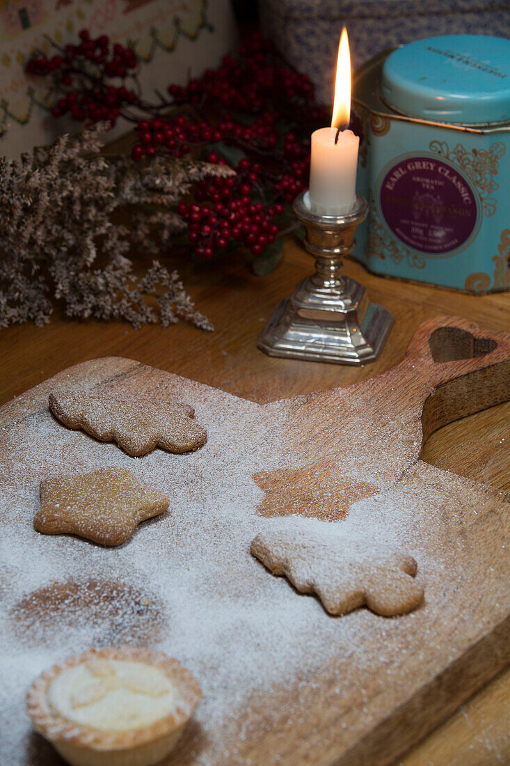 Lit candle with Christmas biscuits on chopping board in London home England UK