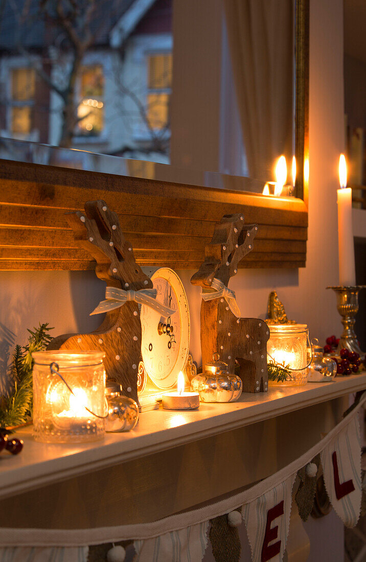 Kerzen und Weihnachtsschmuck auf dem Kaminsims in einem Haus in London, England, UK