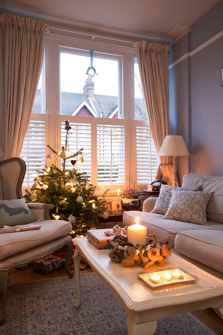 Lit candle on coffee table with Christmas tree at window in London home England UK