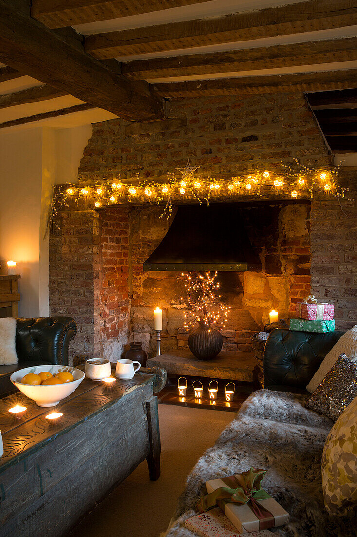 Lit fairylights on exposed brick fireplace in Kent living room England UK