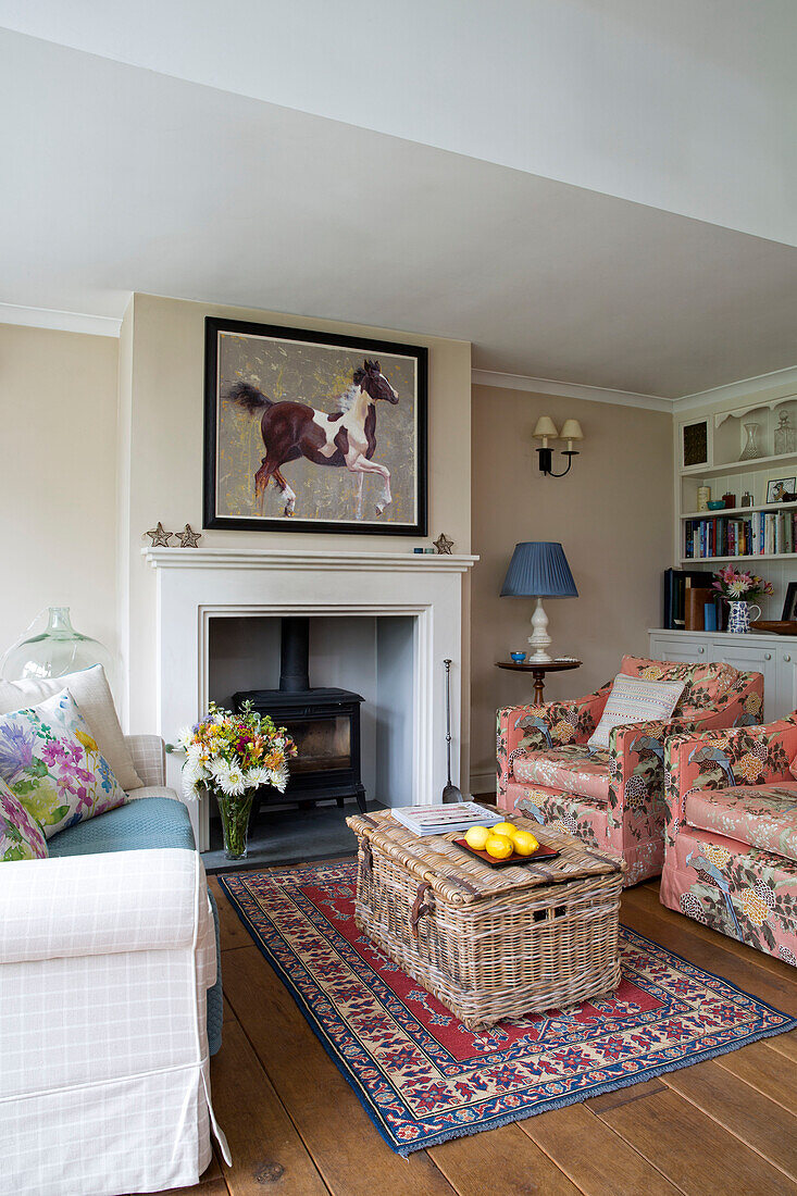 Equestrian artwork above fireplace with picnic hamper and rug in living room of Berkshire home England UK