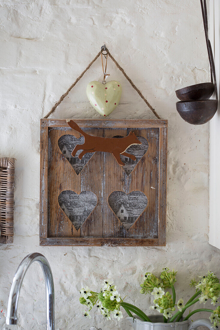 Holzkunstwerk und Schöpfkellen mit Herzen hängen in der Küche eines renovierten viktorianischen Schulhauses in West Sussex England UK