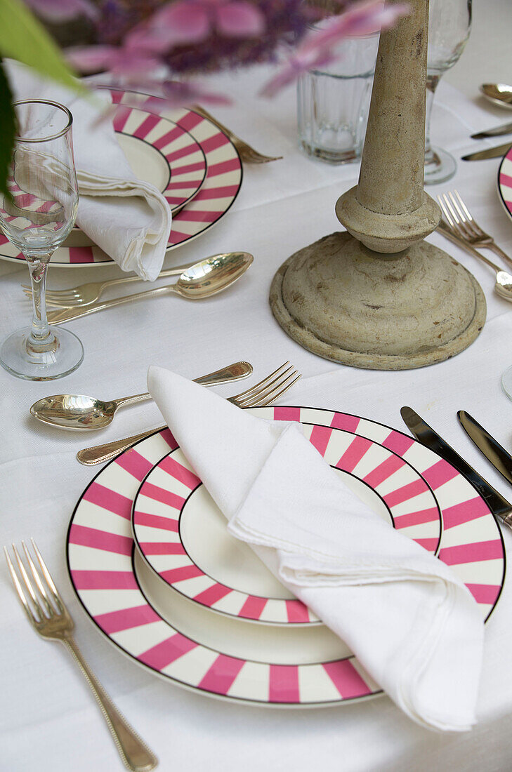 Pink striped plates on dining table in West Sussex home England UK