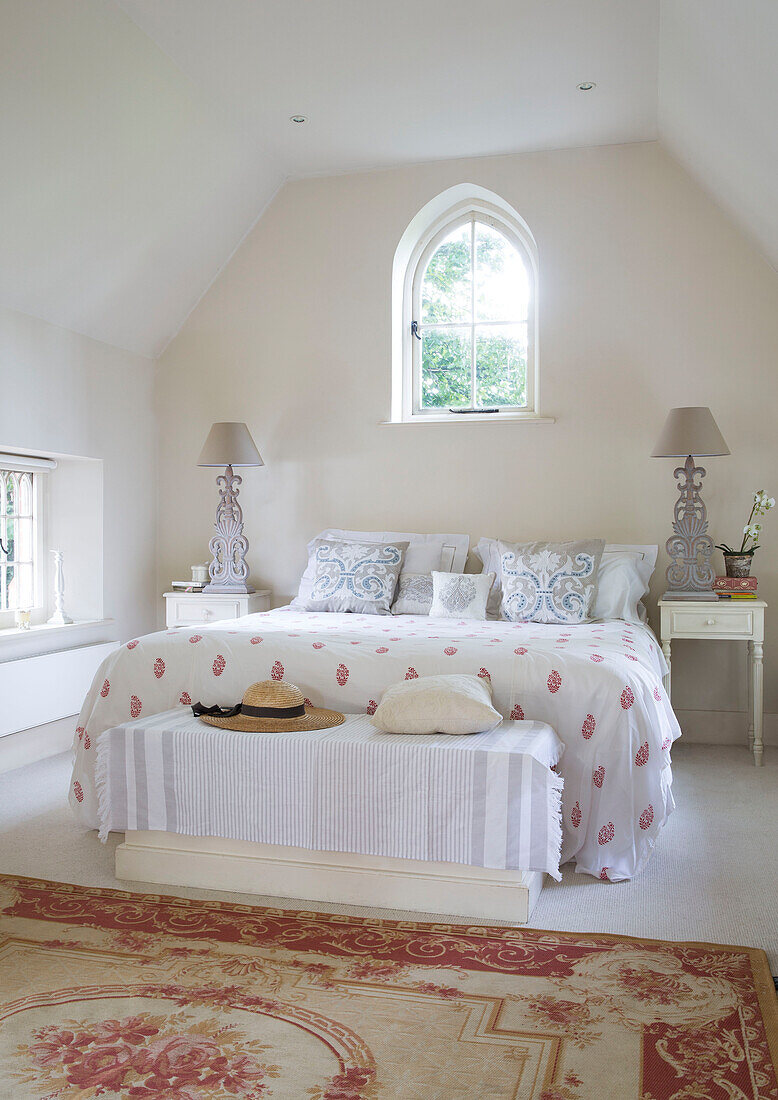 Double bed below pointed arch window in renovated Victorian schoolhouse West Sussex England UK