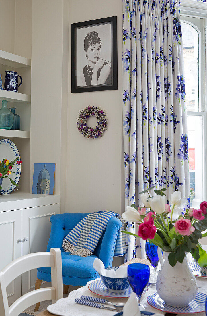 Cut flowers on dining table with blue and white curtains in London townhouse UK