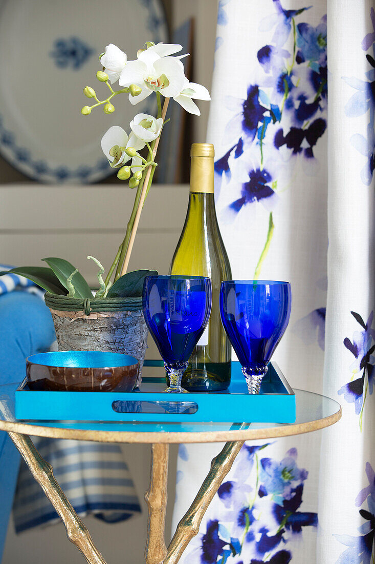 Blue glasses and orchid with white wine on side table in London townhouse UK