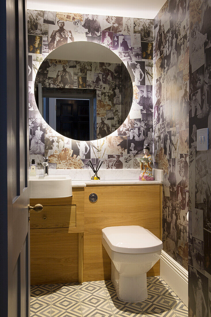 Beleuchteter runder Spiegel mit schwarzer und weißer Drucktapete im Badezimmer eines Londoner Stadthauses, UK
