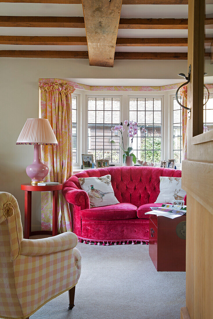 Pink sofa and lamp in window of Grade II listed cottage in Hampshire England UK