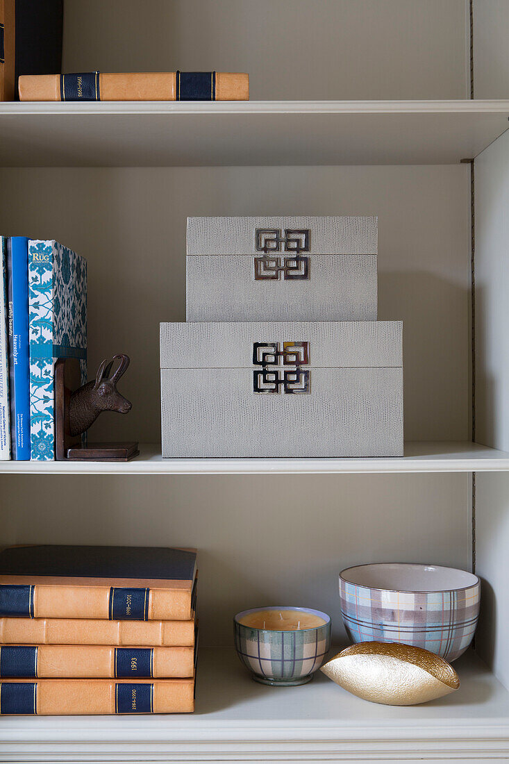 Aufbewahrungsboxen und Bücher mit festem Einband und Schalen auf einem Regal in einem Haus in London, England UK