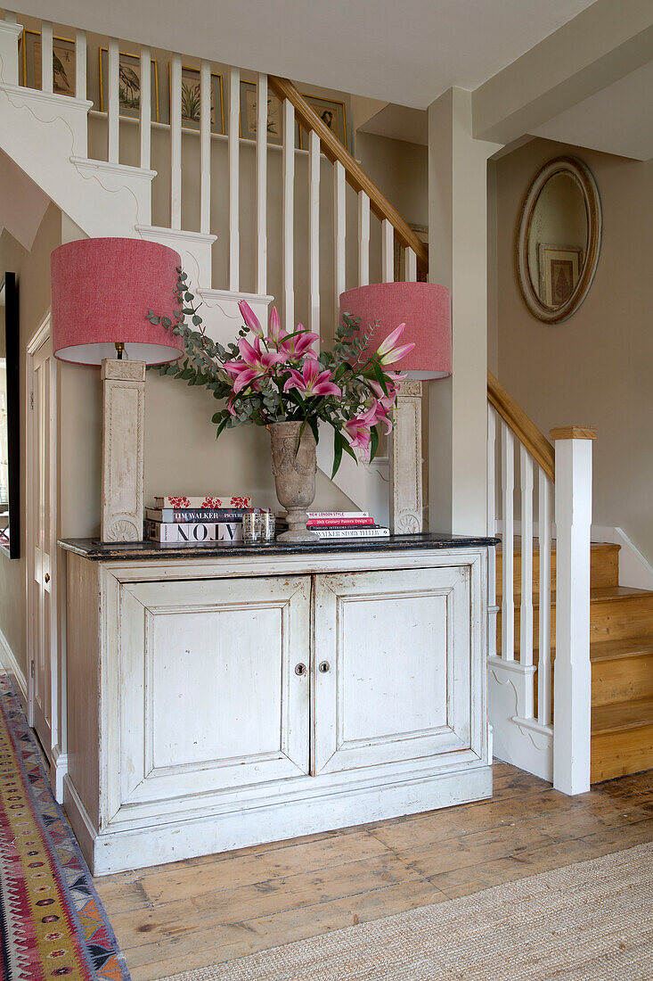 Matching pair of pink lampshades in side unit with banisters in entrance of Sussex home England UK