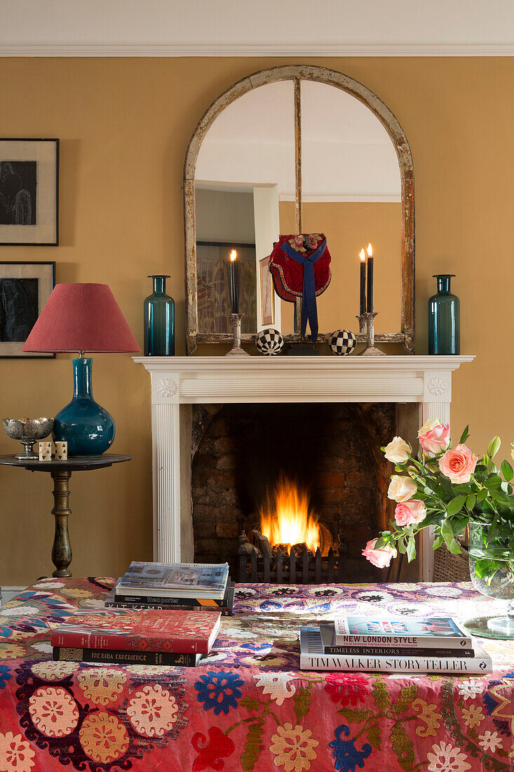 Crochet cover on ottoman in front of lit fire in living room of Sussex home England UK