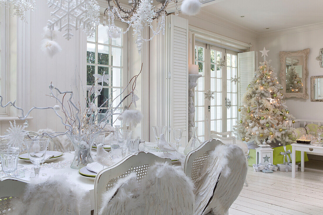 Mit Engelsflügeln geschmückte Esszimmerstühle am Tisch in einem offenen Raum mit Weihnachtsbaum in einem Haus in Südlondon England UK