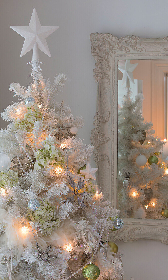 Stern auf einem künstlichen Weihnachtsbaum mit Lichterketten und Kugeln in einem Haus in South London England UK