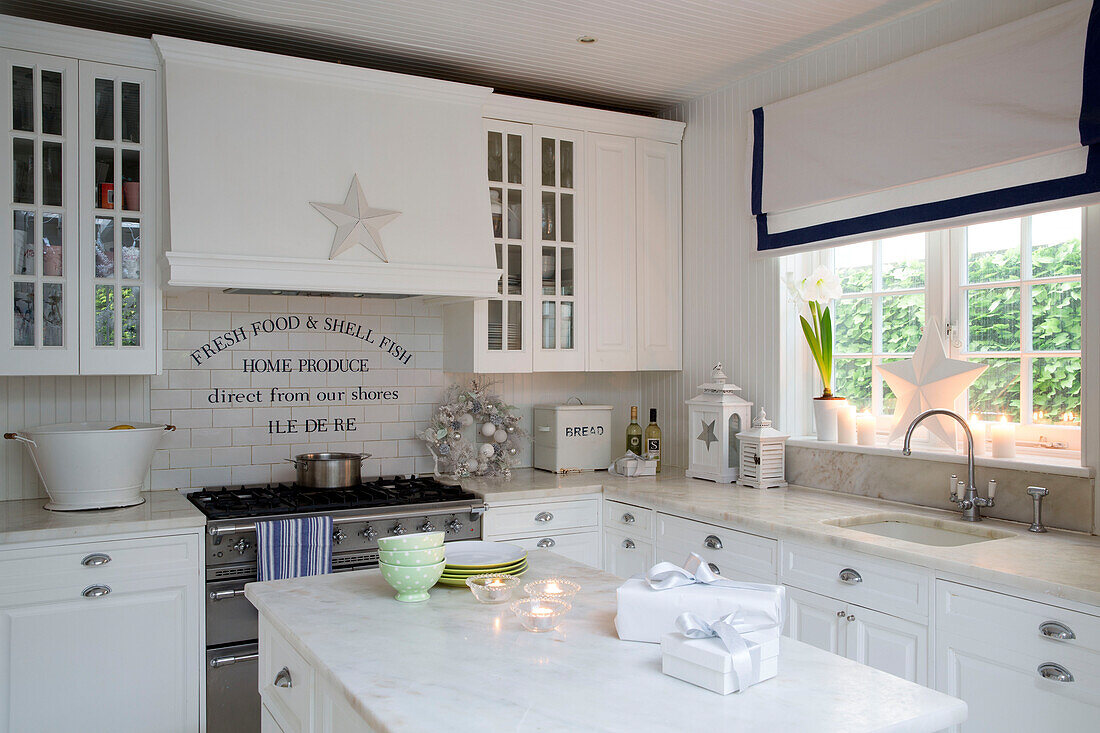 Lit candles in kitchen with lettering on tiled splashback above hob in South London home England UK