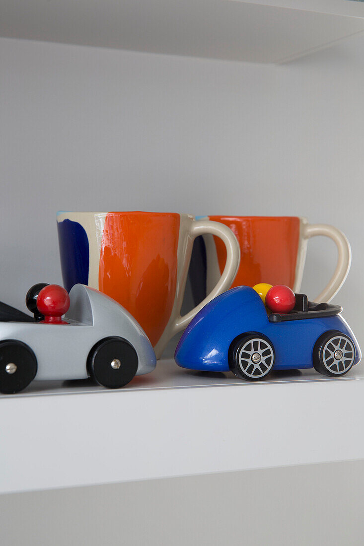 Spielzeugautos und Keramiktassen auf einem Regal in einem Haus in Sussex, England, UK