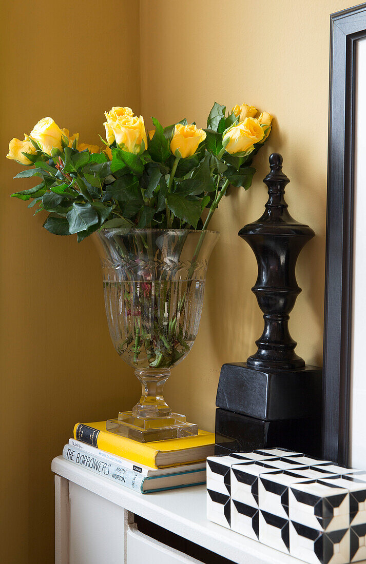 Geschnittene Rosen und schwarzes Ornament mit Büchern im Schlafzimmer eines Londoner Stadthauses UK