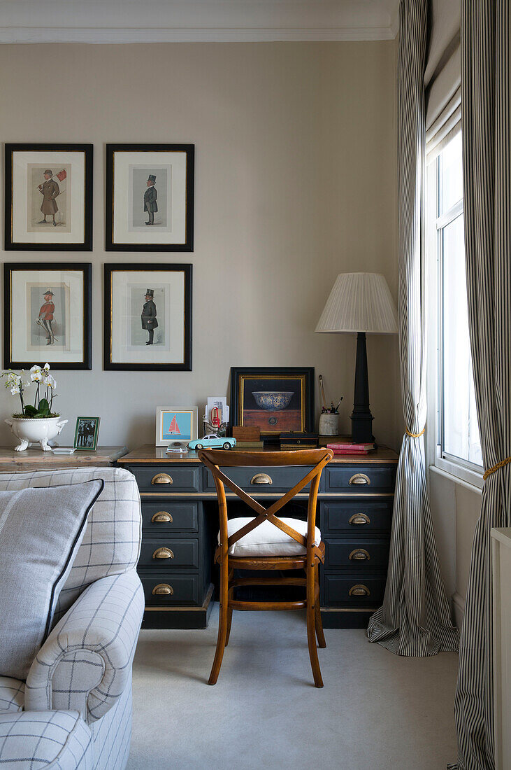 Holzstuhl am Schreibtisch mit gerahmten Drucken in einer Wohnung in einem Londoner Stadthaus UK