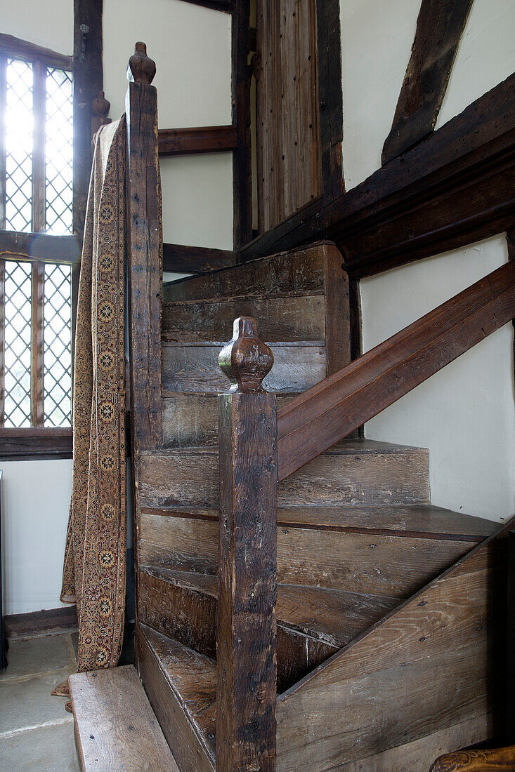 Alte Holztreppe und Geländer mit Stoff an Bleiglasfenster in Bauernhaus mit Holzrahmen Kent UK